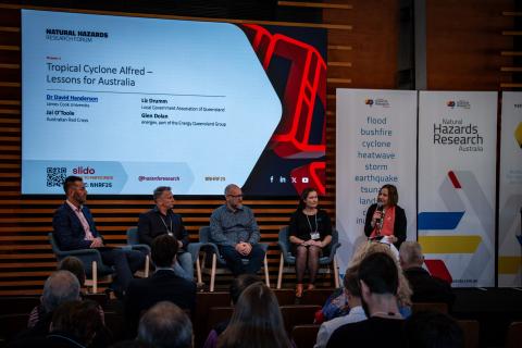 Five people sitting up on stage in front of audience
